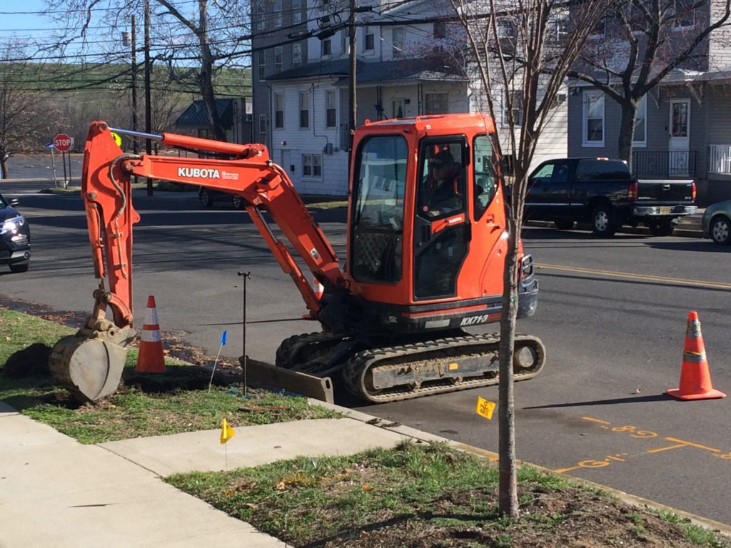 A small orange tractor is parked on the side of the road.