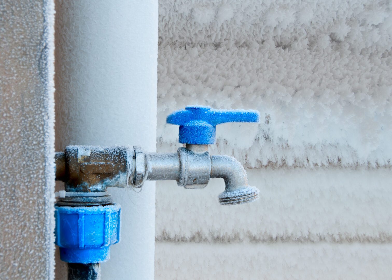 A blue faucet is on the side of a pipe.